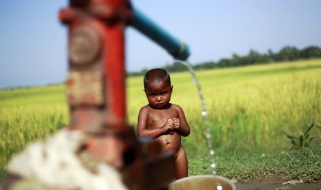    Seorang anak pengungsi berdiri di belakang pompa air di sebuah kamp pengungsi bagi warga muslim yang terlantar akibat aksi kekerasan awal tahun ini luar Sittwe, Myanmar,  Selasa (30/10).   (Soe Zeya Tun/Reuters)