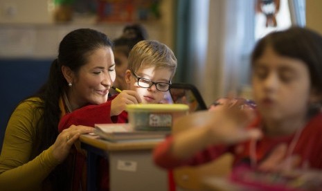 Seorang anak penyandang sindroma down sedang belajar menulis dibantu seorang guru di sekolah di Budapest, Hungaria.