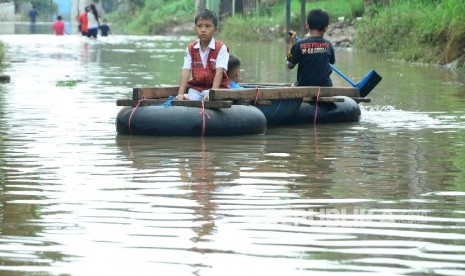 Seorang anak pulang sekolah dibonceng temannya menggunakan rakit di Jl Cibadak, Kecamatan Dayeuhkolot, Kabupaten Bandung.