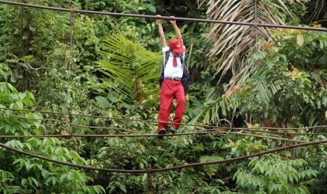 Seorang anak Sekolah Dasar di Padang, Sumatera Barat harus meniti tali jembatan yang rusak ini untuk menuju ke sekolah.