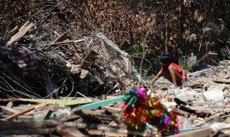 Seorang anak yang terkena dampak dari gusuran mencari harta benda nya setelah tempat tinggalnya diratakan dengan tanah di bantaran Kali Ancol Kawasan Pinangsia, Jakarta Barat, Kamis (28/5).