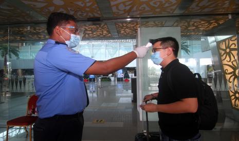 Seorang anggota Aviation Security (Avsec) memeriksa suhu tubuh calon penumpang pesawat di pintu masuk keberangkatan Bandara Supadio, Kabupaten Kubu Raya, Kalimantan Barat, Sabtu (26/12). Epidemiolog dari Griffith University Australia Dicky Budiman mengatakan surat keterangan swab palsu bisa terjadi karena regulasi yang dikeluarkan belum dipersiapkan secara optimal.