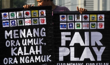 Seorang anggota dari Republik Aeng-aeng dan Pasoepati memegang poster bertemakan pemilu damai saat aksi kampanye damai di Bundaran HI, Jakarta, Ahad (6/4).