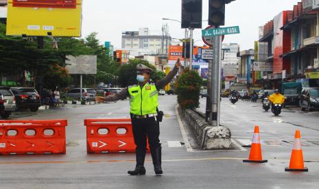 Seorang anggota kepolisian berdiri di depan jalan masuk kawasan pusat perdagangan saat penyekatan di Jalan Gajahmada, Pontianak, Kalimantan Barat, Kamis (1/7/2021). Pemerintah Kota Pontianak memperpanjang dan memperketat pemberlakuan pembatasan kegiatan masyarakat (PPKM) mikro di wilayah setempat terhitung mulai hari ini hingga 14 Juli 2021, karena Pontianak telah masuk dalam zona merah penyebaran COVID-19.