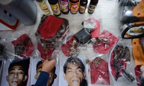 Seorang anggota kepolisian menunjukan barang bukti tindak kejahatan berupa pistol dan minuman keras saat rilis operasi bina kusuma di Lapangan Parkir Ditlantas Polda Metro Jaya, Selasa (3/2). (Republika/Raisan Al Farisi)