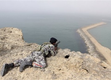 Seorang anggota militer Iran mengambil posisi siaga di pengeboran minyak Iran di pantai laut Oman. 