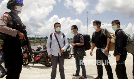 Seorang anggota polisi mengawal sejumlah warga negara China yang terdampar di perairan Rote Ndao setibanya di Lantamal VII Kupang, NTT, Kamis (30/1/2020).