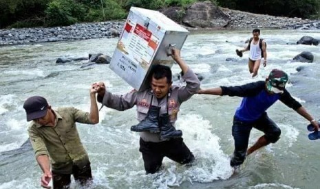 Seorang anggota Polri membawa kotak suara pemilu yang beirisi hasil Pemilu 2014 menyeberangi derasnya arus sungaisungai