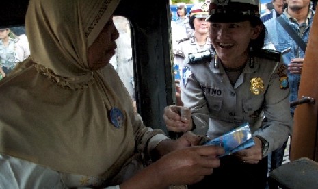 Seorang anggota Polwan menyematkan pin pada seorang penumpang angkot ketika memperingati Hari Anti Kekerasan Terhadap Perempuan dan Anak di Monumen Perjuangan Polri Surabaya, Jatim, Senin (26/11).