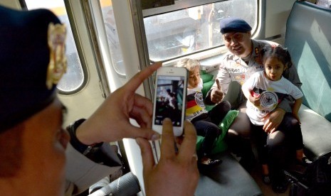 Seorang anggota Sat Brimobda Jatim berfoto bersama anaknya di dalam gerbong KA, sebelum pemberangkatan ke Jakarta, di Stasiun Pasar Turi Surabaya, Selasa (19/8). 