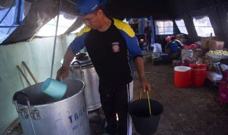 Seorang anggota Tagana memasak nasi untuk dibagikan kepada pengungsi korban gempa bumi Lombok di dapur umum tempat pengungsian di Pemenang, Lombok Utara, NTB. 