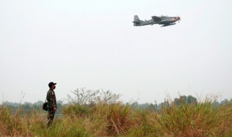 Seorang anggota TNI AU mengamati pesawat EMB 314 Super Tucano yang akan melakukan patroli perbatasan Ambalat di tengah kabut asap, Tarakan, Kalimantan Utara, Selasa (20/10).