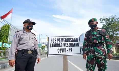 Seorang anggota TNI dan Polri berjaga di Pos Pemeriksaan Standar Kesehatan COVID-19 di Jalan Ahmad Yani, Kota Gorontalo, Gorontalo, Rabu (13/1/2021). Personel TNI, Polri dan Satpol PP terus menggelar razia masker untuk meningkatkan kesadaran masyarakat dalam upaya pencegahan penyebaran COVID-19.