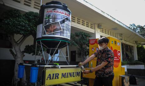 Seorang mengisi air melalui instalasi air siap minum 