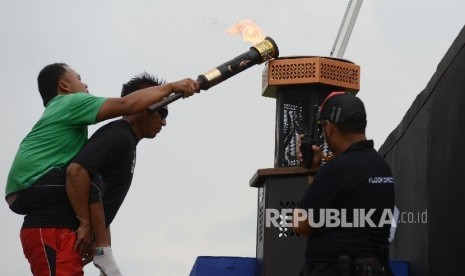 Seorang atlet Pekan Paralimpik Nasional (Peparnas) menyalakan obor api Peparnas saat mengikuti gladi resik di Stadion Siliwangi, Bandung, Jawa Barat, Jumat (14/10). 