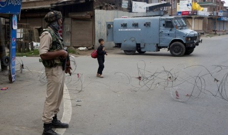 Seorang bocah berjalan melewati tentara paramiliter India setelah membeli roti saat jam malam di Srinagar, Kashmir yang dikuasai India, Selasa (6/8).