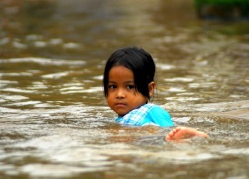 Seorang bocah bermain ditengah genangan banjir dikawasan Kampung Melayu Kecil, jakarta Selatan, Kamis (23/2). (Agung Supriyanto)