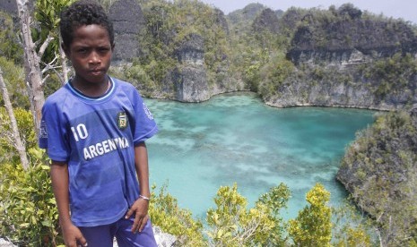 Seorang bocah berpose dengan latar belakang telaga bintang di Raja Ampat, Papua Barat, Senin (2/11). 