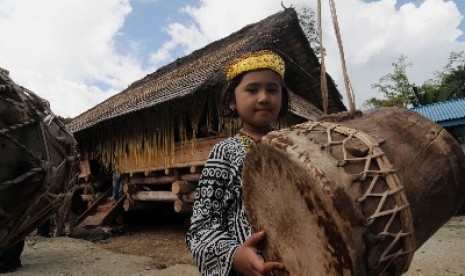 Seorang bocah berpose di depan rumah adat Lobo yang baru diresmikan pemugarannya di Desa Toro, Kulawi Selatan, Sigi, 