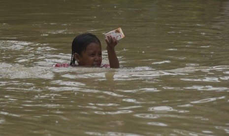 Seorang bocah berusaha melintasi banjir di Baureno, Bojonegoro, Jawa Timur, Jumat (2/12). 