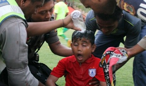 Seorang bocah diberi air setelah terkena gas air mata yang dilepaskan oleh Polisi saat terjadi kerusuhan pada pertandingan sepakbola antara Persipura melawan Persija di stadion Mandala Jayapura, Papua, Minggu (13/05). Kerusuhan di picu aksi pemukulan pemai