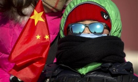 Seorang bocah laki-laki dengan memegang bendera Cina di Lapangan Tiananmen di Beijing, Sabtu, 23 Januari 2016. Suhu dingin di Beijing mencapai titik terendah dalam 30 tahun, yakni minus 17 derajat Celcius.