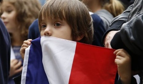 Seorang bocah laki-laki memegang bendera Prancis dalam aksi solidaritas di luar Kedutaan Besar Prancis di Bogota, Kolombia, Sabtu, 14 November 2015.  