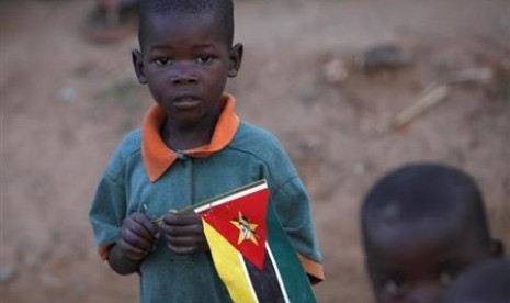 Seorang bocah memegang bendera Mozambik di pinggiran ibu kota Maputo.