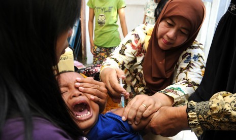 Seorang bocah mendapatkan vaksin DPT (Difteri, Pertusis dan Tetanus) tambahan saat vaksin difteri massal berbagai usia di Desa Plandi, Jombang, Jawa Timur.