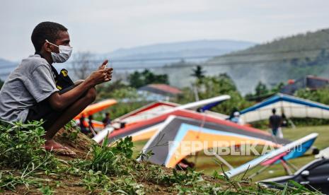 Seorang bocah menonton pertandingan gantole nomor ketepatan mendarat PON Papua di Lapangan Advent, Doyo Baru, Kabupaten Jayapura, Papua, Jumat (24/9/2021). 