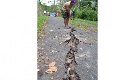 Seorang bocah menunjukkan jalan yang retak akibat gempa bumi di Desa Klangon, Madiun, Jatim, Jumat (26/6).