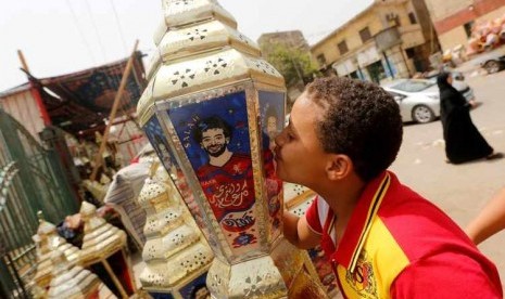 Seorang bocah Mesir mencium lentera hias tradisional yang dikenal dengan nama Fanous bergambar pemain depan sepak bola Mesir, Mohamed Salah.