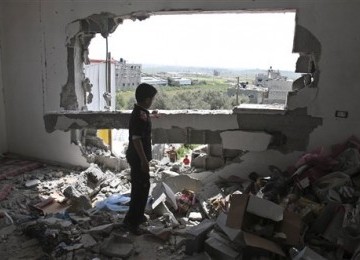 Seorang bocah Palestina memeriksa rumah keluarganya yang hancur akibat serangan udara Israel di timur kota Gaza, Jumat (8/4).