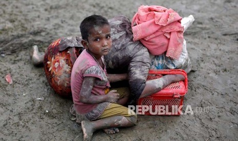 Seorang bocah Rohingya duduk di samping ibunya yang berisitirahat setelah melintasi perbatasan Bangladesh-Myanmar di Teknaf, Rabu (6/9).