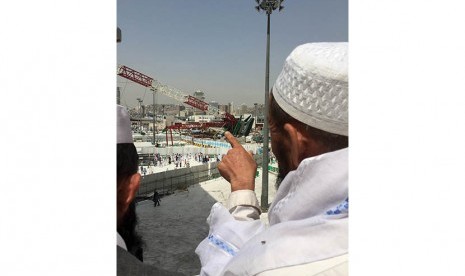 Seorang calon jamaah haji menunjuk ke arah crane proyek perluasan masjid yang jatuh di Masjidil Haram, Makkah, Sabtu (12/9).   (Reuters/Mohamed Al Hwaity)