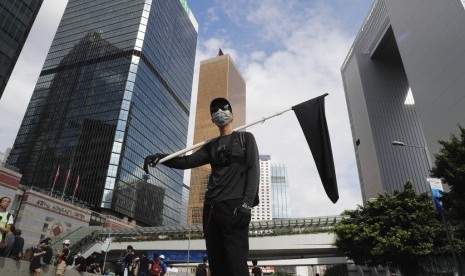 Seorang demonstran memegang bendera hitam sebagai simbol dukacita bagi Hong Kong dalam protes di Hong Kong, Senin (1/7).