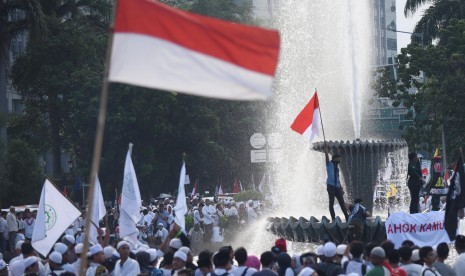 Seorang demonstran mengibarkan bendera dalam aksi dalam aksi 4 November di Jakarta, Jumat (4/11). 