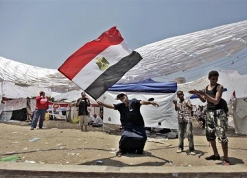 Seorang demonstran Mesir menari seraya melambaikan bendera negaranya dalam unjuk rasa di Tahrir Square, Kairo.