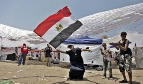 Seorang demonstran Mesir menari seraya melambaikan bendera negaranya dalam unjuk rasa di Tahrir Square, Kairo.