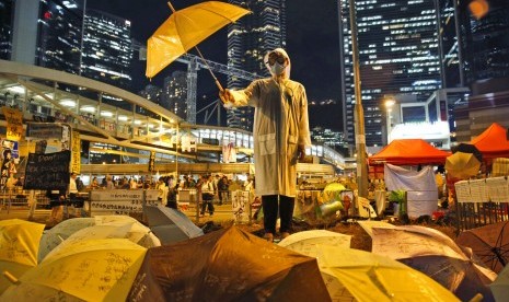 Seorang demonstran prodemokrasi memegang payung di luar markas pemerintah di Hong Kong, 9 Oktober 2014. Pengadilan Hong Kong memvonis bersalah sembilan aktivis prodemokrasi, Selasa (9/4). 