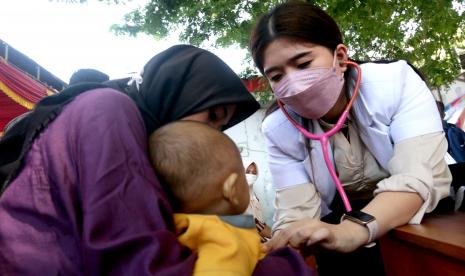 Seorang dokter menggunakan stetoskop untuk mendengarkan irama jantung anak. Pemeriksaan ini dapat mendeteksi penyakit jantung bawaan.