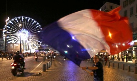 Seorang fan Prancis mengibarkan bendera negaranya di Marseille usai memastikan lolos ke final Piala Eropa 2016.