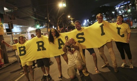 Seorang fans Jerman berfoto bersama suporter Brasil sambil memegang replika trofi Piala Dunia di depan Stadion Maracana, Rio de Janeiro, Ahad (13/7). 