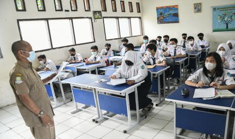 Seorang Guru (kiri) memberikan materi pembelajaran kepada sejumlah murid SMP 29 di Bekasi, Jawa Barat, Senin (4/4/2022). Dinas Pendidikan Kota Bekasi sudah mengizinkan SD dan SMP di wilayah tersebut menjalani PTM (Pembelajaran Tatap Muka) dengan kapasitas 100 persen murid dengan protokol kesehatan Covid-19. PTM 100 persen tidak berarti kelas diisi penuh.