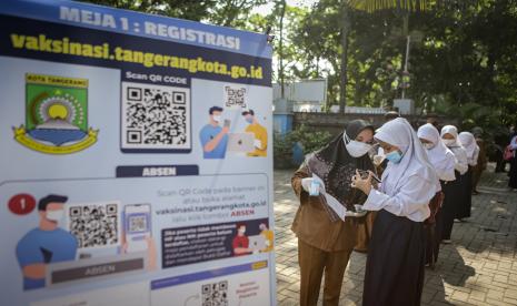 Seorang guru membantu siswa saat pendaftaran vaksinasi secara daring di SMPN 29 Kota Tangerang, Banten, Senin (26/7/2021). Pemerintah Kota Tangerang meluncurkan fitur baru di situs pendaftaran vaksinasi COVID-19 sebagai upaya mempercepat proses administrasi agar peserta vaksin tidak perlu mengantre untuk mendapatkan surat vaksinasi dan bisa meningkatkan target vaksinasi hingga mencapai 25 ribu dosis dari sebelumnya 18 ribu dosis per hari. 