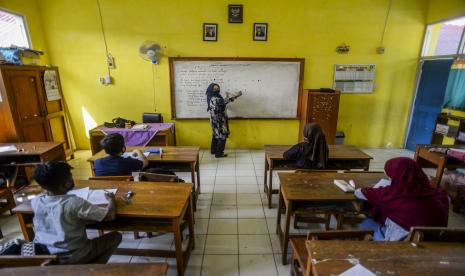 Seorang guru memberikan penjelasan kepada anak-anak saat uji coba pembelajaran tatap muka (PTM) di SDN Cihideung Ilir 5, Ciampea, Kabupaten Bogor, Jawa Barat.