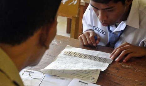 Seorang guru mendampingi siswa yang berkebutuhan khusus.