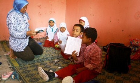 Seorang guru mengajar siswa kelas 2 yang hanya berjumlah lima murid di lantai SDN V Krasak, kec. Jatibarang, Kab. Indramayu, Jabar, Kamis (17/11). Akibat ruang kelas rusak siswa SDN V Krasak terpaksa belajar di rumah huni guru yang terletak di samping bang