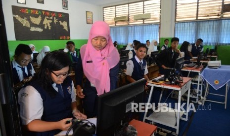 Seorang guru mengarahkan muridnya sesaat sebelum melakukan Ujian Nasional Berbasis Komputer (UNBK) di SMP Negeri 30, Jakarta Utara, Senin (9/5