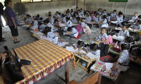 Seorang guru mengawasi siswa kelas 2 belajar di lantai di Sekolah Dasar Negeri 3 Sesetan Denpasar, Bali, Kamis (2/10).